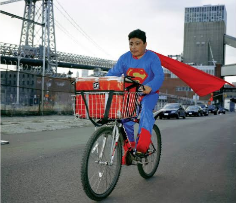 a man dressed in a superman costume riding a bicycle